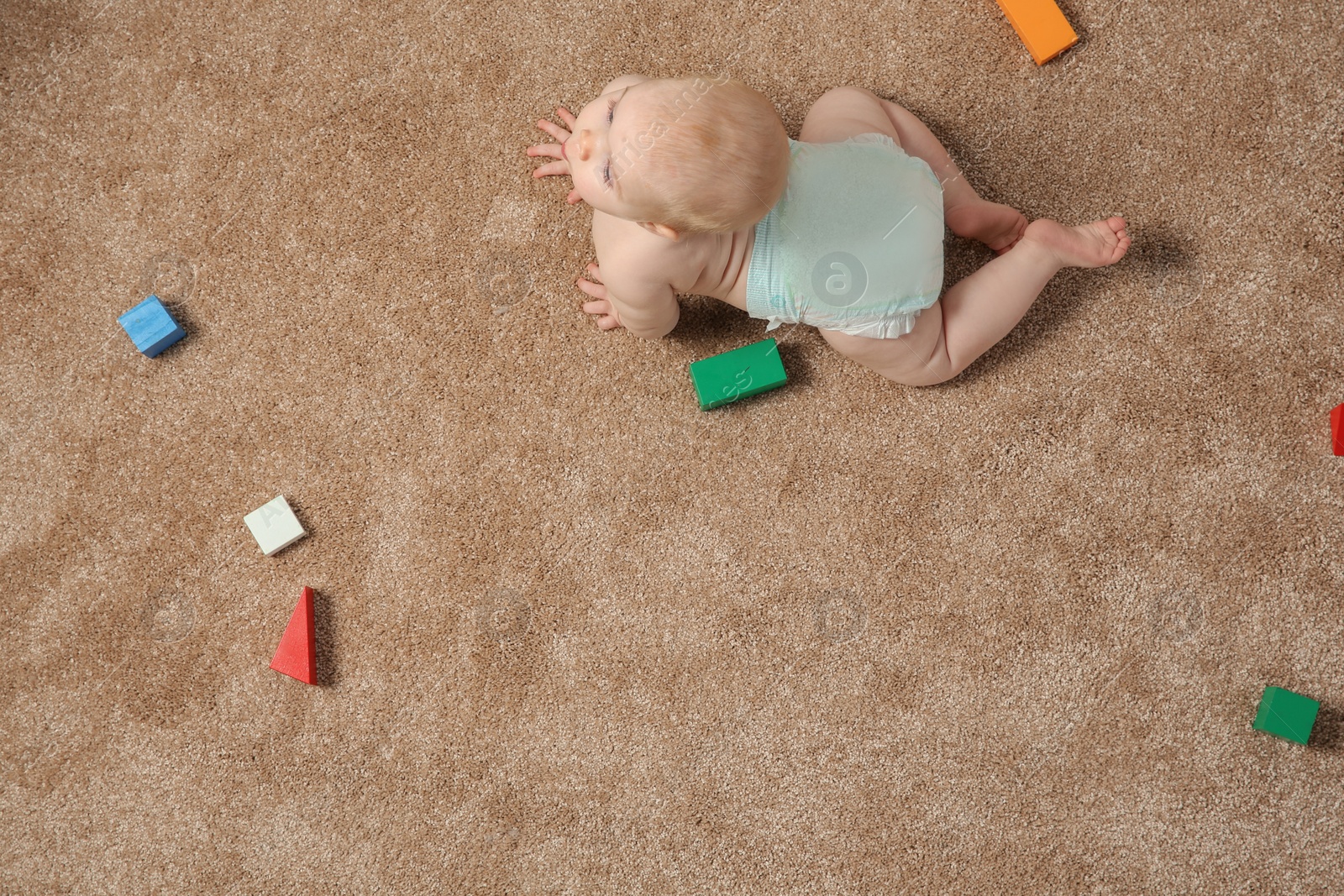 Photo of Cute little baby crawling on carpet with toys, top view. Space for text