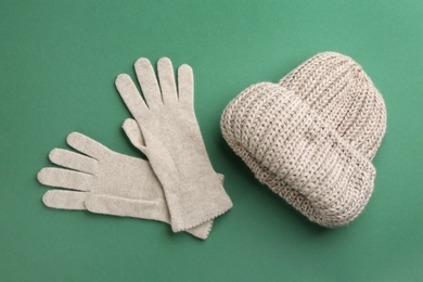 Photo of Woolen gloves and hat on green background, flat lay