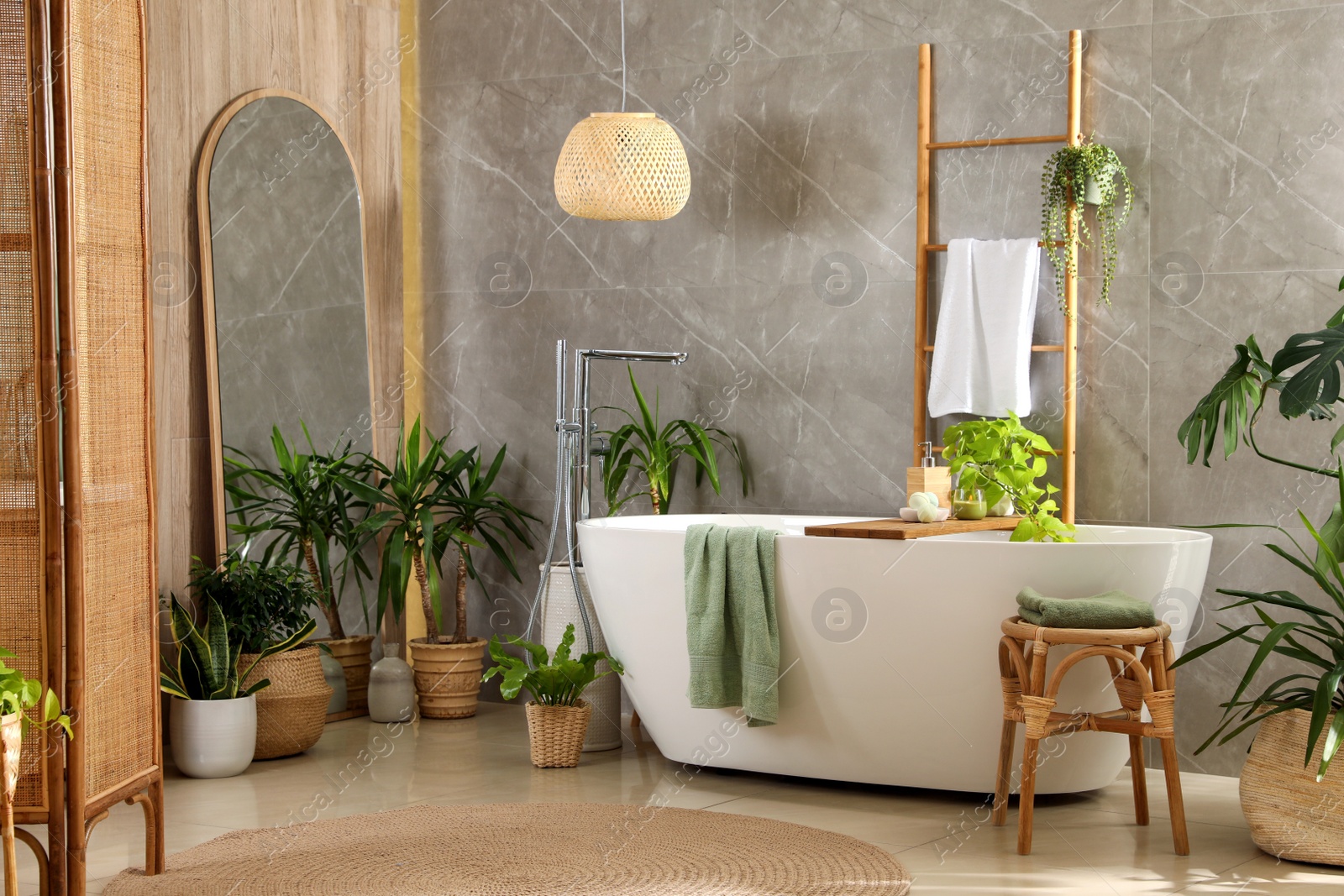 Photo of Modern white tub and beautiful green houseplants in bathroom. Interior design