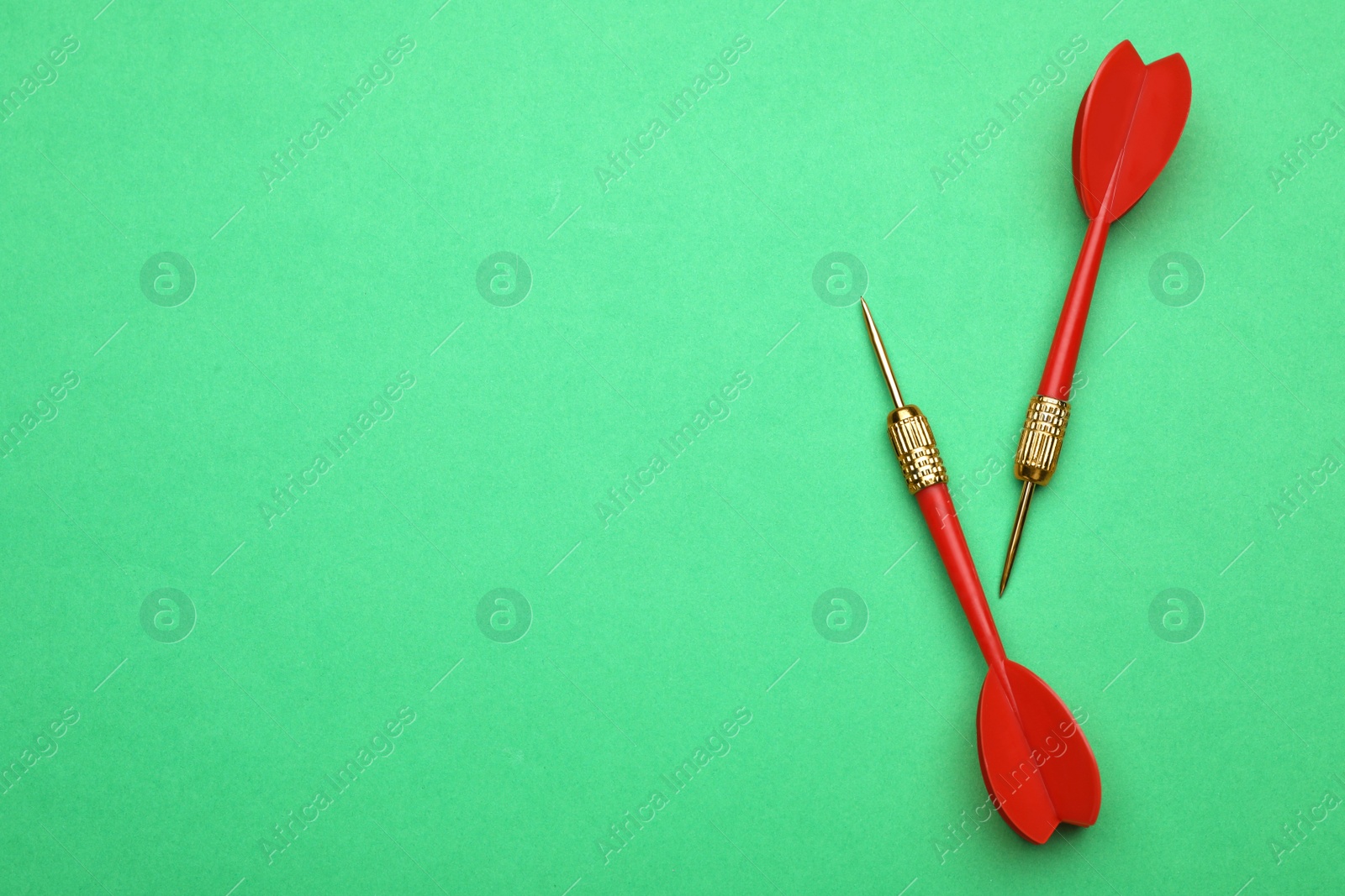 Photo of Red dart arrows on green background, flat lay with space for text