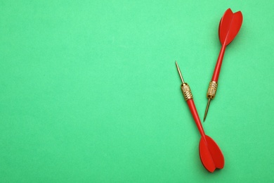 Photo of Red dart arrows on green background, flat lay with space for text