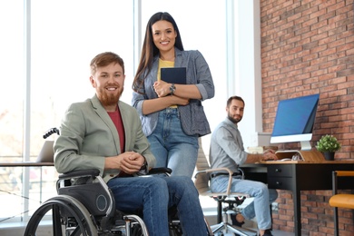 Young man in wheelchair with colleagues at office
