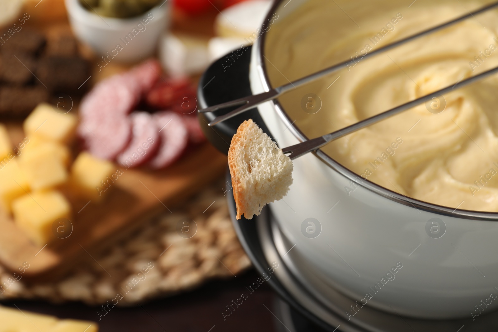 Photo of Fondue with tasty melted cheese, forks and piece of bread on table, closeup. Space for text