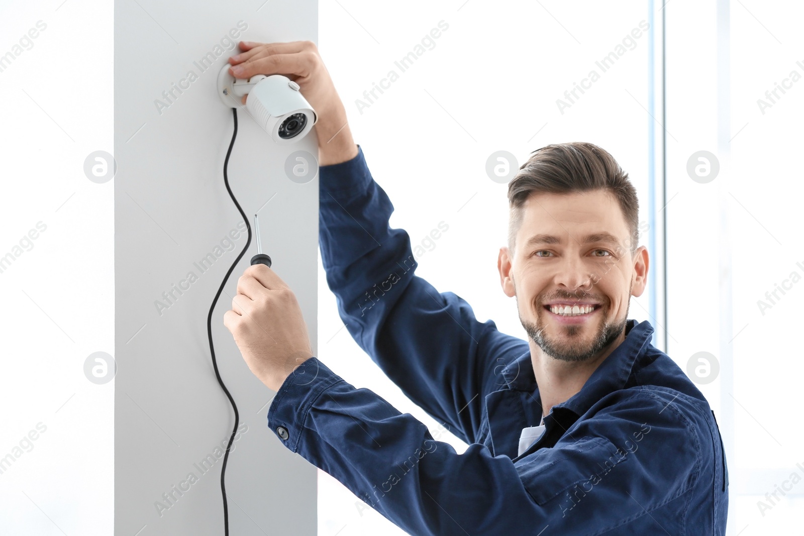 Photo of Technician installing CCTV camera on wall indoors