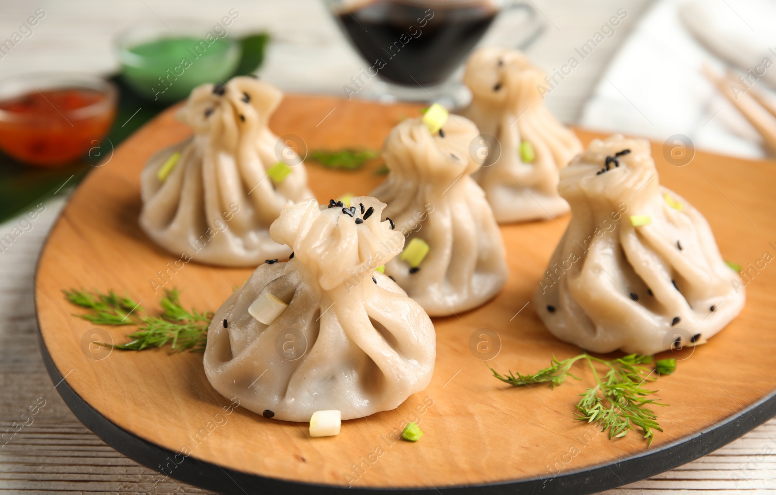 Photo of Wooden plate with tasty baozi dumplings on table, closeup