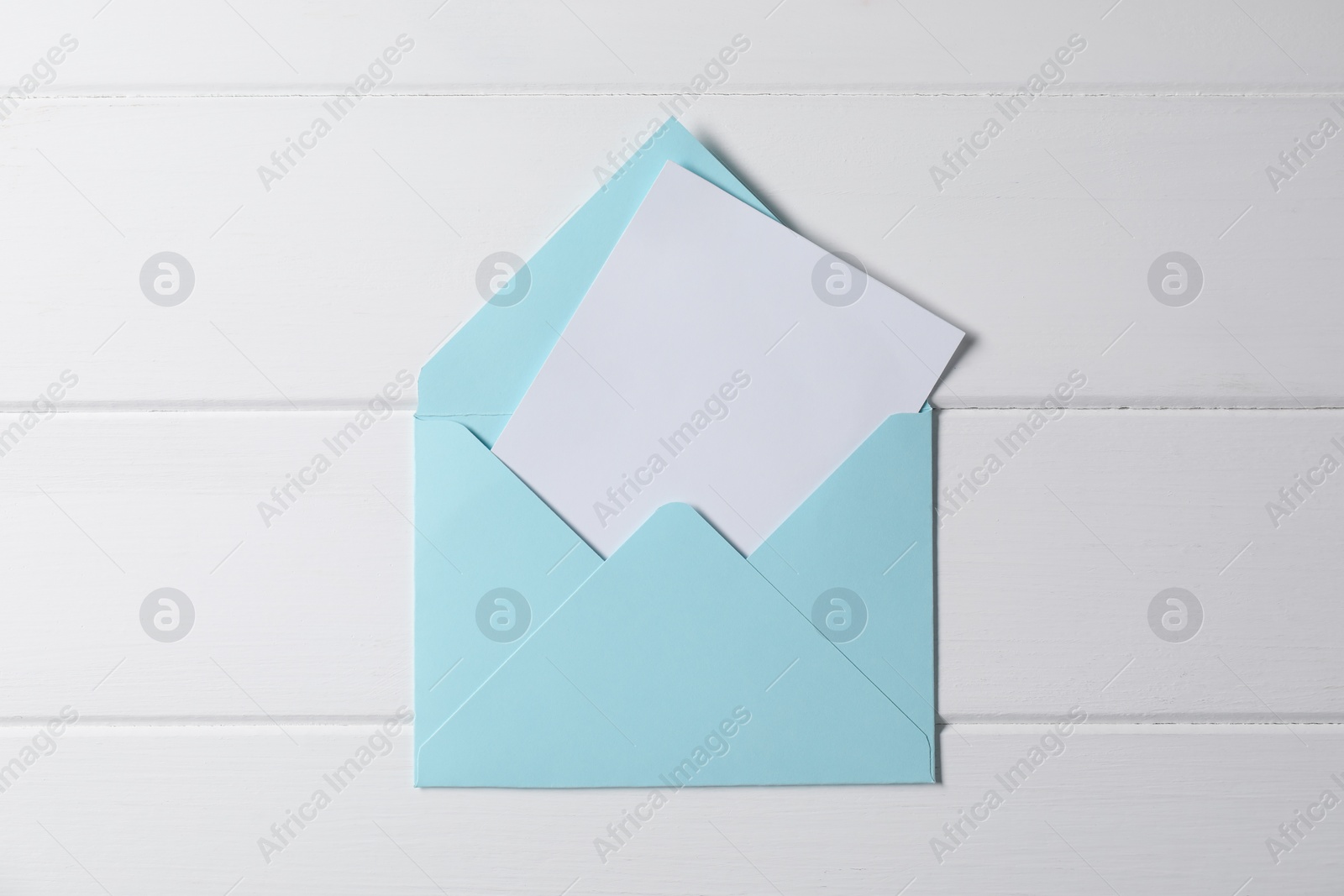 Photo of Letter envelope with card on white wooden table, top view