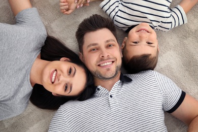 Happy parents and their son lying together on floor, view from above. Family time