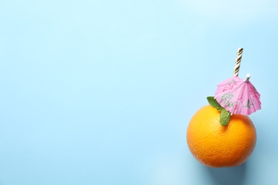 Photo of Creative composition with orange, mint, straw and cocktail umbrella on light blue background. Space for text