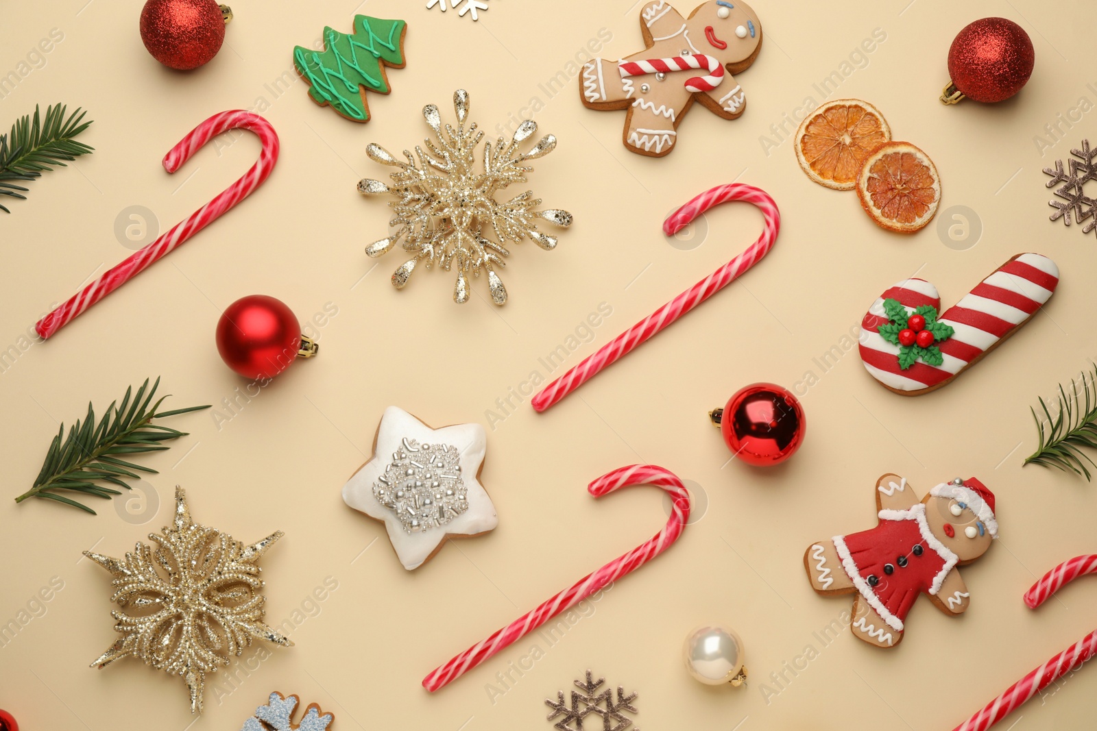 Photo of Flat lay composition with sweet candy canes and Christmas decor on beige background