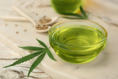 Photo of Glass bowl with hemp oil on table, closeup