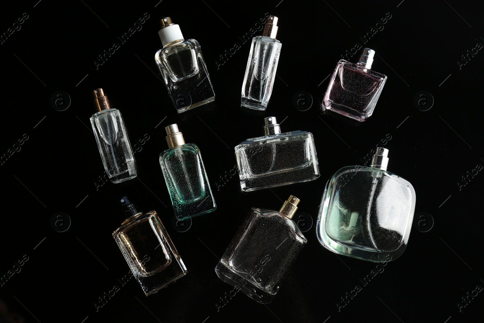 Photo of Perfume bottles on black background, flat lay