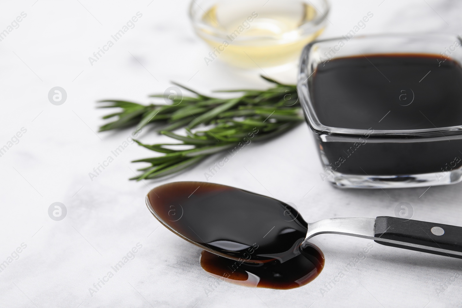 Photo of Organic balsamic vinegar and cooking ingredients on white table, closeup