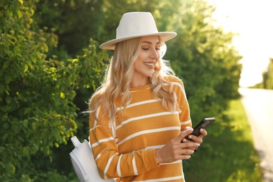 Photo of Happy young woman using smartphone in park on spring day