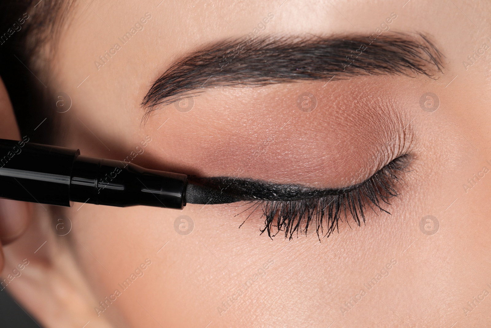 Photo of Beautiful woman applying black eyeliner, closeup view
