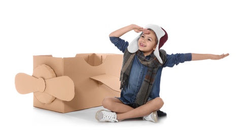 Cute little girl playing with cardboard airplane on white background