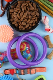 Dry pet food, toys and other goods on light blue background, flat lay. Shop items