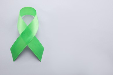 Photo of World Mental Health Day. Green ribbon on color background, top view with space for text