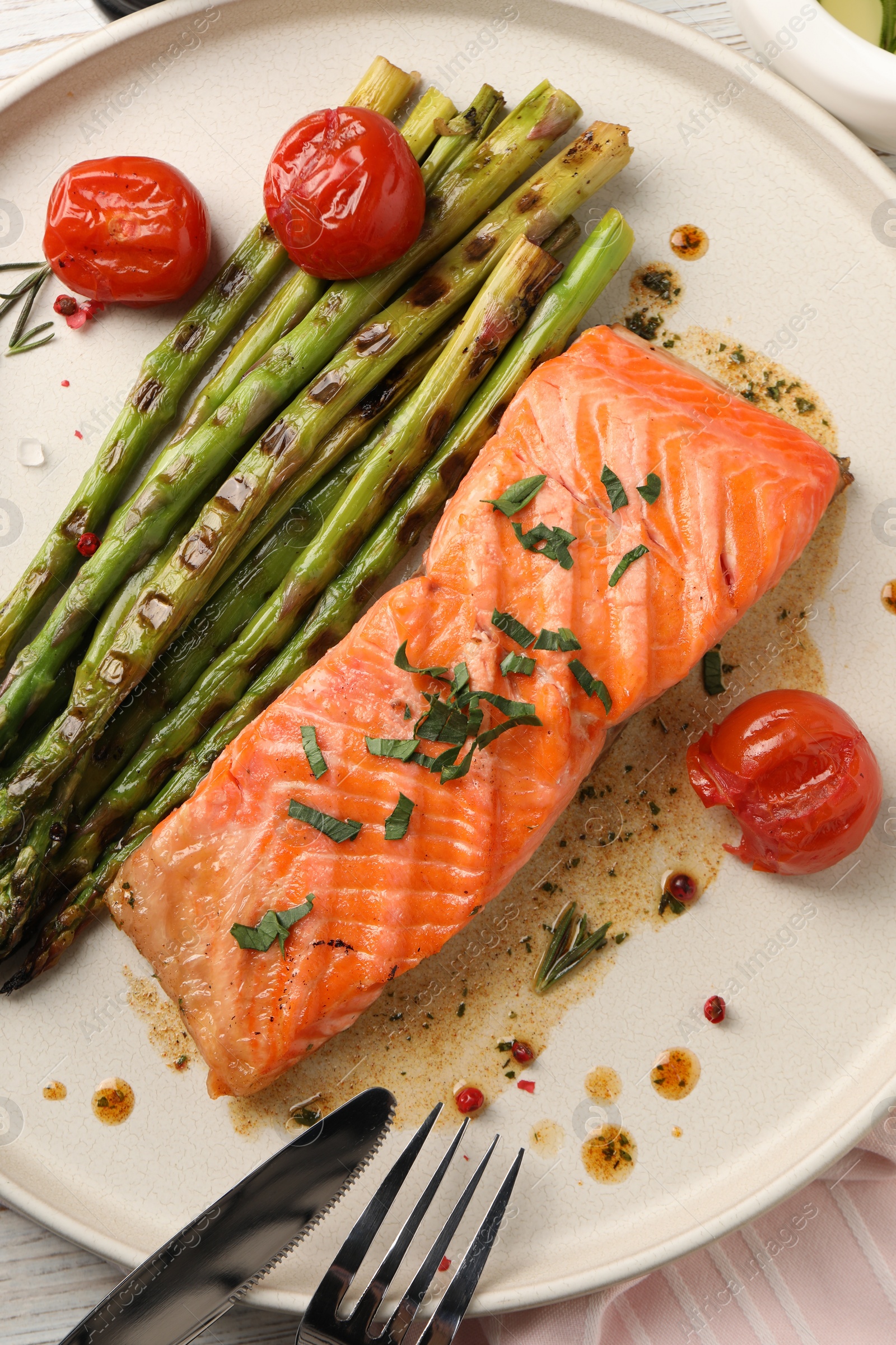 Photo of Tasty grilled salmon with tomatoes, asparagus and spices served on table, top view