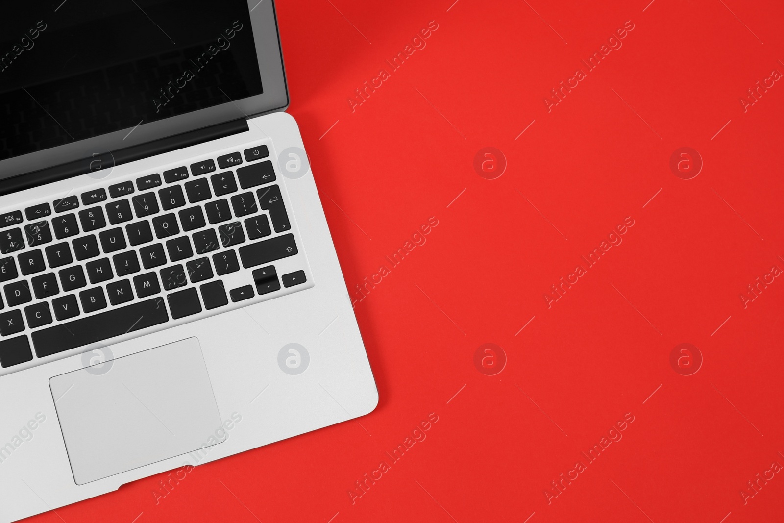 Photo of Modern laptop on red background, top view. Space for text