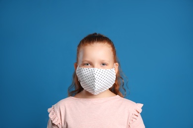 Photo of Preteen girl in protective face mask on blue background