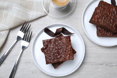 Delicious chocolate brownies served on white wooden table, flat lay