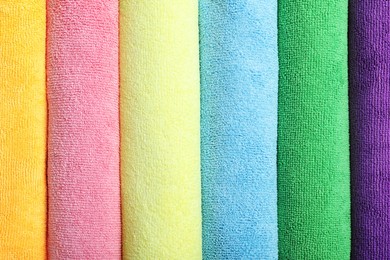 Many colorful microfiber cloths as background, top view