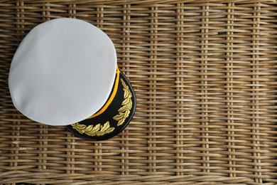 Peaked cap with accessories on wicker surface, top view. Space for text