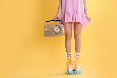Photo of Young woman with roller skates and retro radio on color background, closeup. Space for text