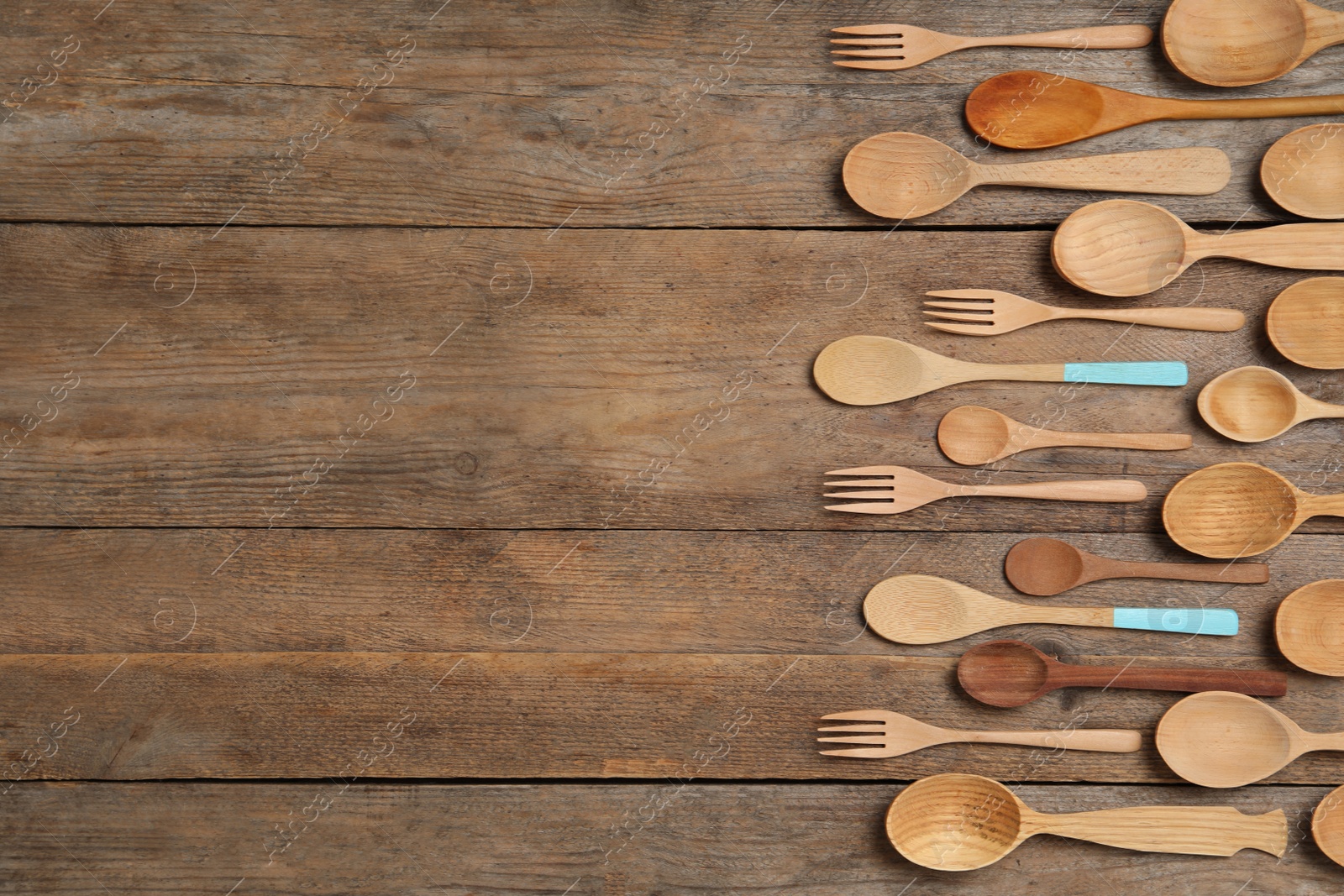 Photo of Many different spoons and forks on wooden table, flat lay with space for text. Cooking utensils