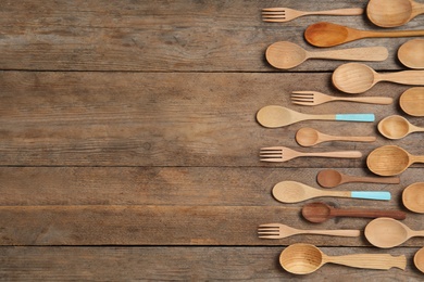 Many different spoons and forks on wooden table, flat lay with space for text. Cooking utensils