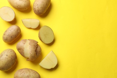 Photo of Fresh raw potatoes on yellow background, flat lay. Space for text