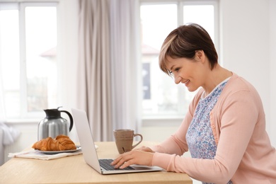 Photo of Senior woman using laptop at table