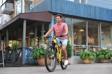 Photo of Handsome young man riding bicycle on city street
