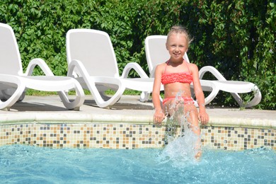 Photo of Happy cute little girl having fun in swimming pool on sunny day