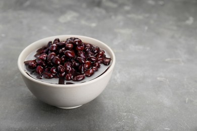 Photo of Bowl of canned kidney beans on grey table. Space for text