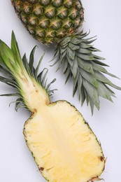 Photo of Whole and cut ripe pineapples on white background, flat lay
