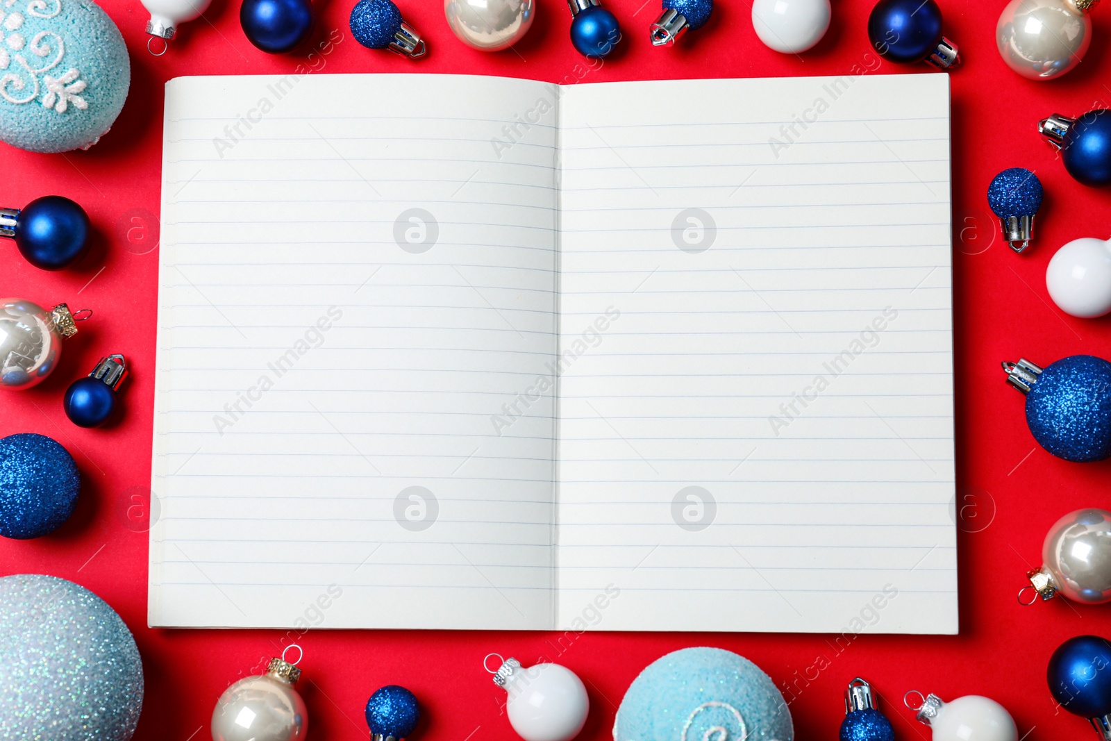 Photo of Flat lay composition with empty notebook and Christmas decorations on red background, space for text. Writing letter to Santa Claus