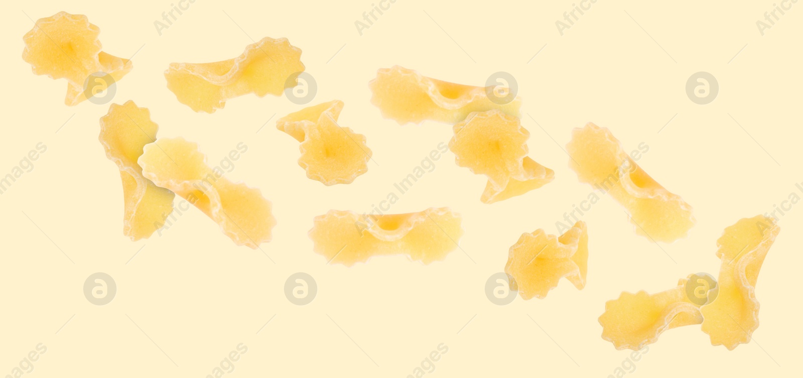Image of Raw farfalline pasta falling on beige background