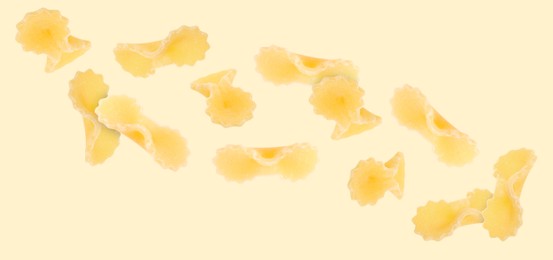 Image of Raw farfalline pasta falling on beige background