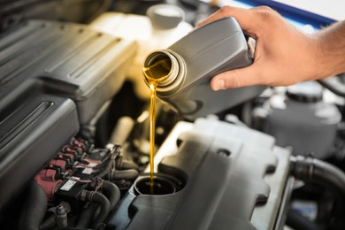 Image of Man pouring motor oil into car engine, closeup. Color accent effect