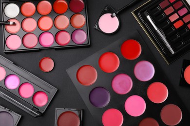 Photo of Flat lay composition with cream lipstick palettes on black background. Professional cosmetic product