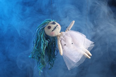 Female voodoo doll with pins and smoke on blue  background