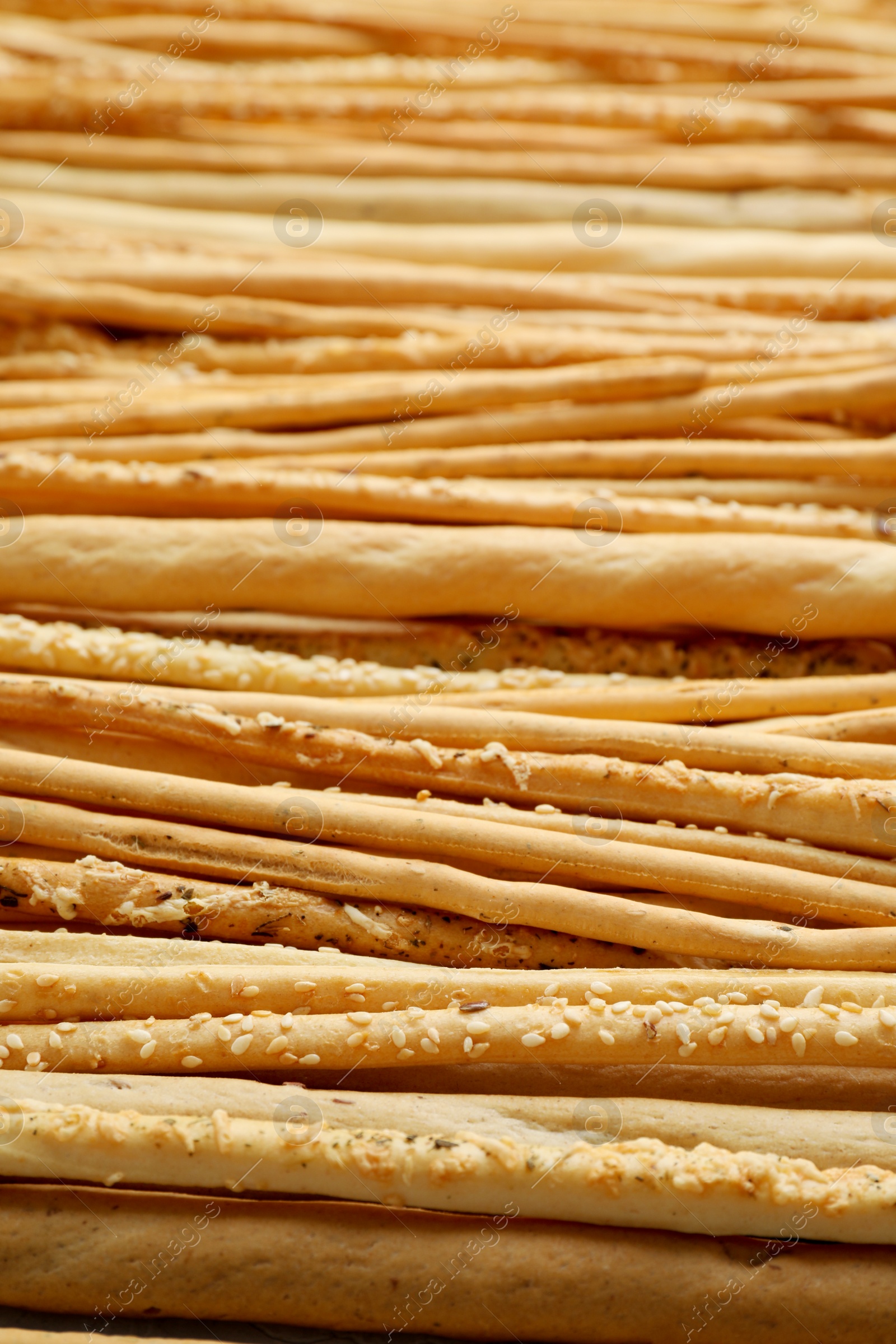 Photo of Delicious grissini sticks with sesame as background, closeup