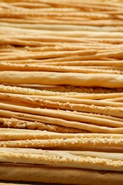 Photo of Delicious grissini sticks with sesame as background, closeup