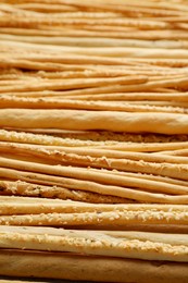 Delicious grissini sticks with sesame as background, closeup