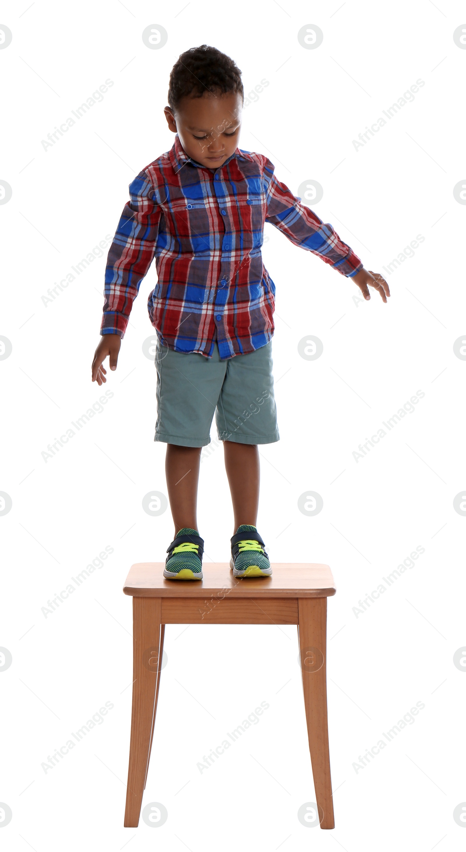 Photo of Little African-American boy standing on stool on white background. Danger at home