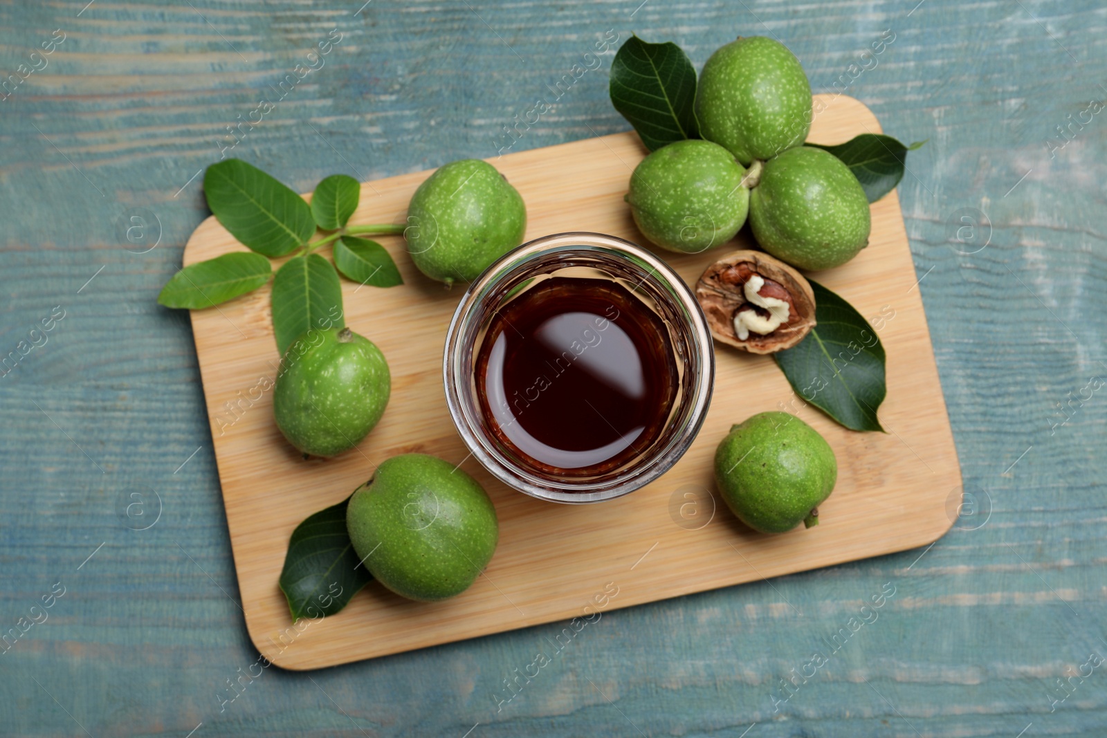 Photo of Delicious liqueur and fresh walnuts on light blue wooden table, top view