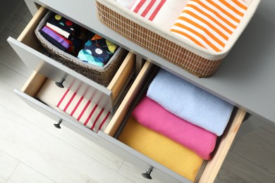 Chest of drawers with different folded clothes indoors, top view