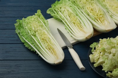 Photo of Cut fresh ripe Chinese cabbages on blue wooden table