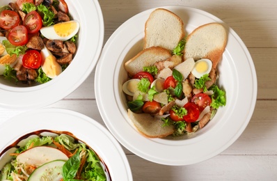 Photo of Plates with different delicious salads on table, top view